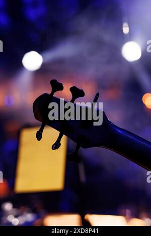 Sintonizzazione di una chitarra Bass, in contrasto con l'effetto bokeh delle luci da concerto Foto Stock