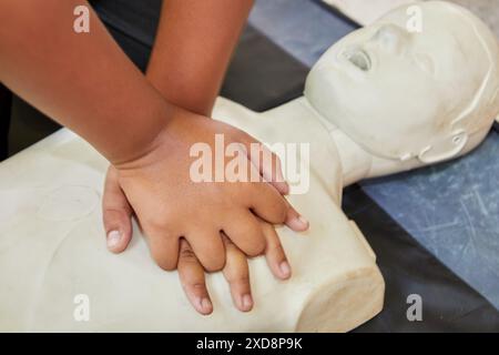 Istruzioni di pronto soccorso RCP con mani corte e manichino RCP in aula Foto Stock