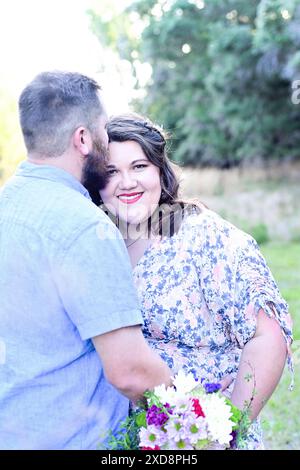 Uomo che bacia una donna incinta sorridente sulla fronte mentre lei h Foto Stock