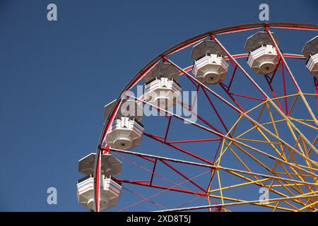 Ruota panoramica contro un cielo blu limpido in un parco divertimenti. Foto Stock