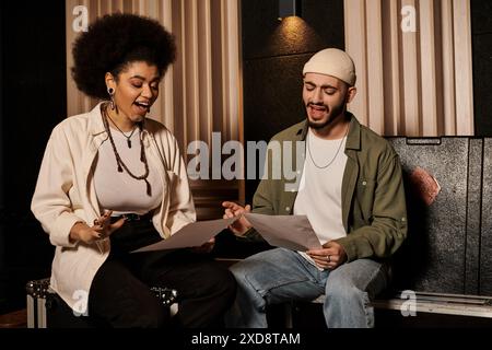 Un uomo e una donna siedono in uno studio di registrazione, collaborando alla musica per le prove della loro band. Foto Stock