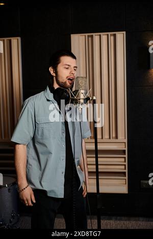 Un uomo di talento canta appassionatamente nel microfono in uno studio di registrazione professionale durante le prove della band. Foto Stock