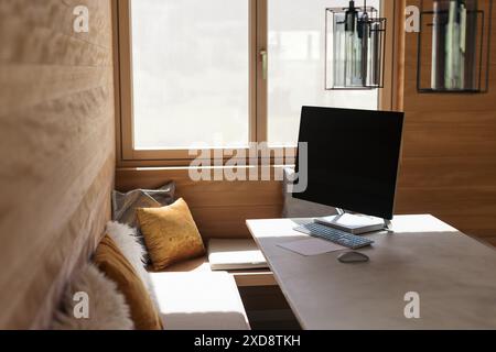 Moderno ufficio domestico con pareti in legno e un computer su una scrivania Foto Stock