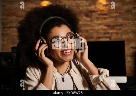 Una giovane donna che indossa le cuffie in uno studio di registrazione, immersa nella produzione musicale per una sessione di prove della band. Foto Stock