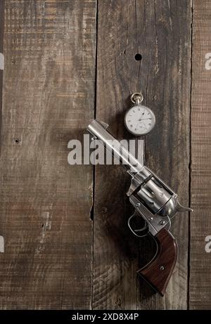 Selvaggio West, a mezzogiorno. Cowboy 6 cannoni e orologio da tasca argento steso su un vecchio tavolo di legno. Cowboy, western, tema. Foto Stock