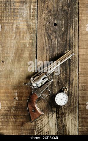 Selvaggio West, a mezzogiorno. Cowboy 6 cannoni e orologio da tasca argento steso su un vecchio tavolo di legno. Cowboy, western, tema. Foto Stock