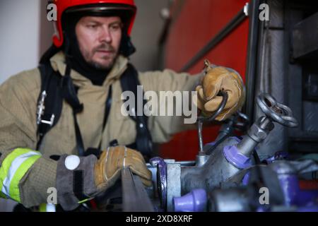 Vigile del fuoco in uniforme con equipaggiamento per motori antincendio in stazione, fuoco selettivo Foto Stock