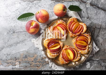 Pesche cotte in pasta sfoglia a forma di cuore con frutta matura e marmellata da vicino in un piatto sul tavolo. Vista dall'alto orizzontale Foto Stock