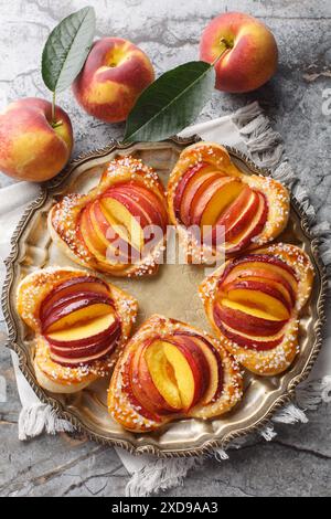 Sfoglia di pesca a forma di cuore con frutta fresca e marmellata da vicino in un piatto sul tavolo. Vista dall'alto verticale Foto Stock