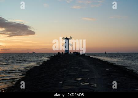 Mulino a vento vecchio stile sul molo roccioso sulla costa dell'isola di usedom lungo il mar baltico della Polonia con un bellissimo tramonto romantico e suggestivo Foto Stock