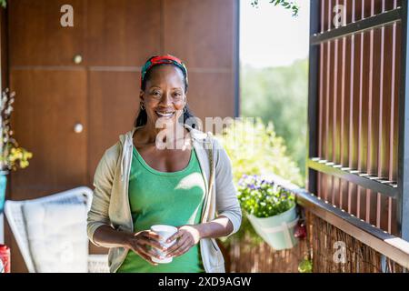 Ritratto di una donna sorridente in piedi sul balcone di casa Foto Stock