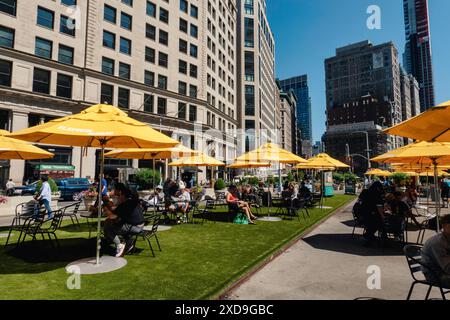 L'area pubblica con posti a sedere a Fifth Avenue e 23rd St. Presenta ombrelli gialli luminosi per ombra, 2024, New York City, Nomad, Stati Uniti Foto Stock