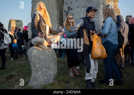 I festeggiatori spiritualmente celebrano il Solstizio d'estate (metà estate e giorno più lungo) tra le antiche pietre tardo-neolitiche di Stonehenge, il 21 giugno 2024, nel Wiltshire, in Inghilterra. Il solstizio d'estate è il giorno più lungo dell'emisfero settentrionale e la notte più breve dell'anno, quando l'asse terrestre è inclinato nel punto più vicino al sole e i pagani dicono che l'antico monumento è un luogo sacro che collega la Terra, la Luna, il Sole e le stagioni. Stonehenge è stata costruita in tre fasi tra il 3.000 a.C. e il 1.600 a.C. Stonehenge è di proprietà dell'English Heritage che dice che 15.000 visitatori sono stati ammessi Foto Stock