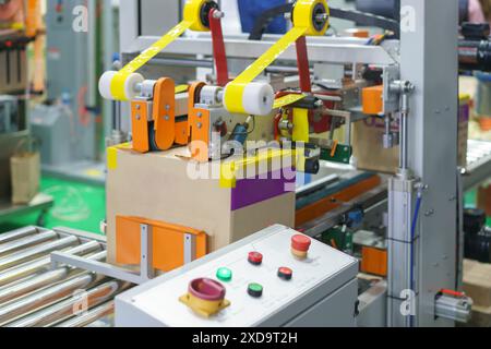 La macchina sembra utilizzare del nastro per chiudere e sigillare automaticamente le scatole di cartone Foto Stock