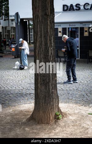 Una giovane donna e un uomo anziano stanno su Alter Markt guardando i loro cellulari, Colonia, Germania. ###EDITORIALE USA SOLO## eine junge Frau und ein Foto Stock