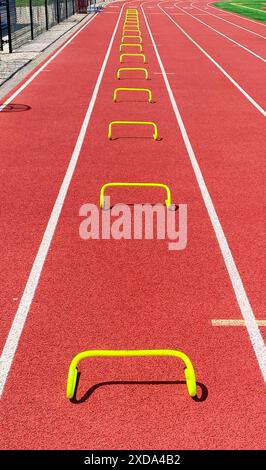 Guarda in basso i mini ostacoli gialli disposti per l'allenamento di velocità in corsia su una pista per gli allenamenti di corsa. Foto Stock