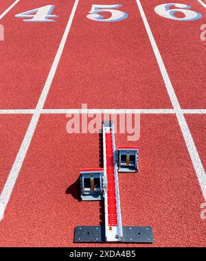 Guardando in basso i corridori che iniziano la corsia 5 su una pista rossa da cui uno sprinter deve uscire. Foto Stock