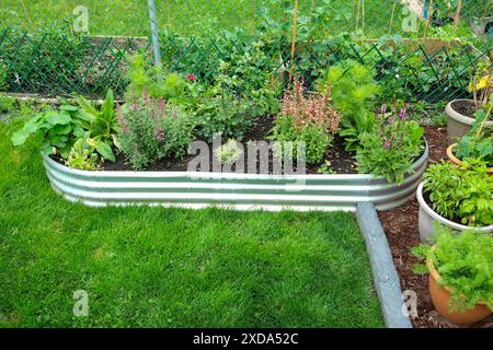 Perfetto per gli inquilini, questo giardino commestibile portatile dispone di un letto da giardino rialzato in metallo galvanizzato con un'area pacciamata divisa da bordi in mattoni. Foto Stock