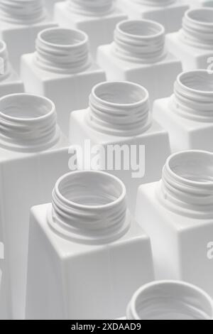 Gruppo numeroso di bottiglie di plastica bianca vuote pronte per essere riempite o riciclate, confezionamento o linea di produzione, background industriale astratto Foto Stock