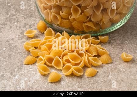Cospargere di pasta guscio cruda con un vaso di vetro da vicino Foto Stock