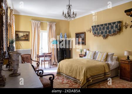 Camera da letto gialla con mobili antichi e pareti appese in un hotel ristrutturato in pietra risalente al 1770 a Saulieu, Borgogna, Francia. Foto Stock