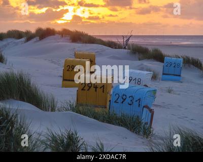 Colorate sdraio su una spiaggia sabbiosa al tramonto con dune ricoperte di erba sullo sfondo, Juist, Mare del Nord, Germania Foto Stock