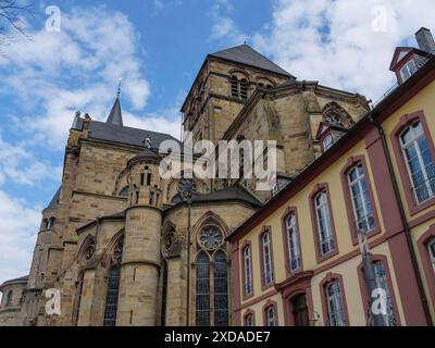 Grande chiesa gotica con numerose finestre, edifici storici e cielo blu, treviri, germania Foto Stock