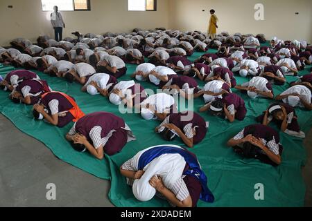 Mumbai, India. 21 giugno 2024. Gli studenti della scuola della N.H.English Academy si allungano durante una sessione di yoga condotta in occasione della giornata Internazionale di Yoga. L'esecuzione di regolari esercizi di yoga offre vantaggi significativi nel ridurre lo stress, promuovere il benessere fisico e mentale che a sua volta porta gioia, felicità e tranquillità. (Foto di Ashish Vaishnav/SOPA Images/Sipa USA) credito: SIPA USA/Alamy Live News Foto Stock