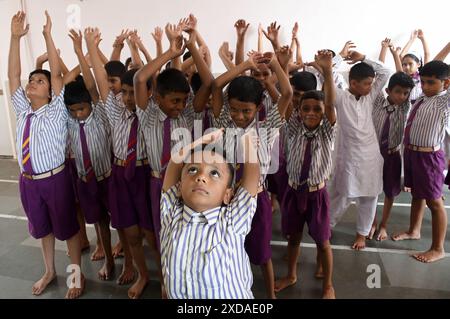 Mumbai, India. 21 giugno 2024. I giovani studenti della scuola della N.H.English Academy partecipano ad una sessione di yoga condotta in occasione della giornata Internazionale dello Yoga. L'esecuzione di regolari esercizi di yoga offre vantaggi significativi nel ridurre lo stress, promuovere il benessere fisico e mentale che a sua volta porta gioia, felicità e tranquillità. (Foto di Ashish Vaishnav/SOPA Images/Sipa USA) credito: SIPA USA/Alamy Live News Foto Stock