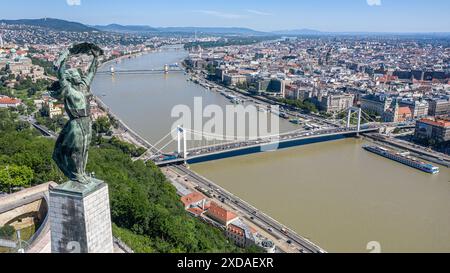 Budapest, Ungheria. 21 giugno 2024: Panorama della capitale ungherese e statua della libertà sulla Cittadella del colle Gellért, eretta nel 1947 in ricordo della liberazione sovietica della città durante la seconda guerra mondiale. Oggi gli ungheresi commemorano il 80° anniversario di una rete unica nella storia dell'Olocausto in Europa: le case della stella gialla, parte delle "leggi ebraiche". Dal 21 giugno 1944 fino all'istituzione del ghetto, 220.000 ebrei mirati furono obbligati a vivere in edifici designati dopo essere stati espulsi dalle case. Come ghetto, le case servivano come fase preparatoria per la deportazione. Crediti: Kevin Izorce/Alamy Live News Foto Stock