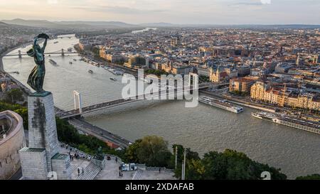 Budapest, Ungheria. 20 giugno 2024: Panorama della capitale ungherese e statua libertà/libertà sulla Cittadella del colle Gellért, eretta nel 1947 in ricordo della liberazione sovietica della città durante la seconda guerra mondiale. Gli ungheresi commemorano il 80° anniversario di una rete unica nella storia dell'Olocausto in Europa: Le case della stella gialla, parte delle "leggi ebraiche". Dal 21 giugno 1944 fino all'istituzione del ghetto, 220.000 ebrei mirati furono obbligati a vivere in edifici designati dopo essere stati espulsi dalle case. Come ghetto, le case servivano come fase preparatoria per la deportazione. Crediti: Kevin Izorce/Alamy Live News Foto Stock