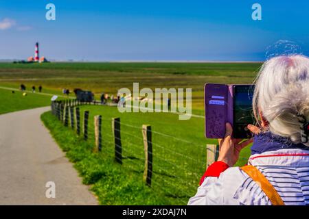 Donna, fotografata con smartphone, faro, Mare del Nord, diga, Westerhever, Schleswig Holstein, Germania Foto Stock