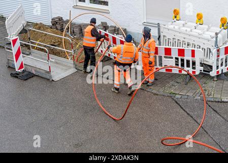 Operai edili che posano cavi in fibra ottica, trincee per cavi, cantiere, espansione in fibra ottica, connessione domestica, accesso a Internet ad alta velocità, uso residenziale Foto Stock