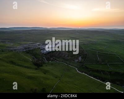 Un tranquillo tramonto su Malham Cove, una delle principali attrazioni turistiche situate nel North Yorkshire, caratterizzato da lussureggianti campi verdi e dalle iconiche formazioni calcaree Foto Stock