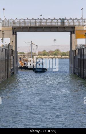 Un rimorchiatore trasporta una barca a vela dahabiya a due alberi nella chiusa di Esna sul fiume Nilo in Egitto. Foto Stock