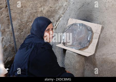 Una donna egiziana vestita in modo tradizionale siede al forno del pane nel villaggio di Bisaw su un'isola nel Nilo a circa 90 km a nord di Assuan. Foto Stock