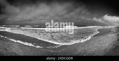 Immagine in bianco e nero che cattura una vista panoramica della costa dell'Oceano Atlantico in un giorno d'estate. Le Whitecaps crescono le onde blu mentre si scontrano Foto Stock