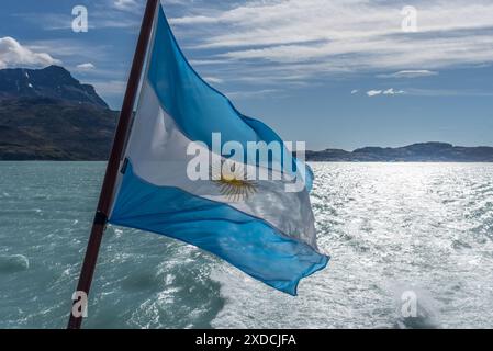 Una bandiera argentina blu e bianca con una stella gialla sta sventolando sull'acqua Foto Stock