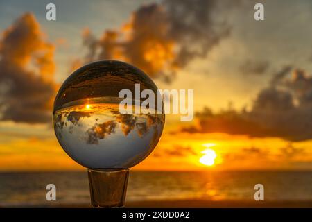 Questo time lapse è stato catturato con una sfera di cristallo per catturare il cielo colorato. tramonto mozzafiato sul mare al crepuscolo. Una scena di luce arancione colorata Foto Stock
