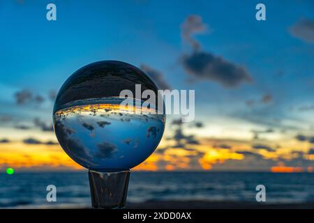 Questo time lapse è stato catturato con una sfera di cristallo per catturare il cielo colorato. tramonto mozzafiato sul mare al crepuscolo. Una scena di luce arancione colorata Foto Stock