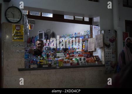 Un vecchio vendeva spuntini al suo stand in una stazione al buio la mattina Foto Stock