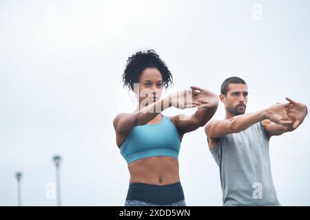 Coppia, braccia all'aperto e stretching per l'esercizio fisico, runner e allenamento sul lungomare per il fitness. Persone, supporto e flessibilità per muscoli o. Foto Stock