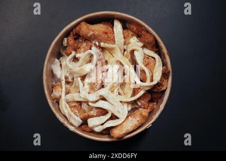 In una ciotola su una superficie scura viene presentato un confortevole piatto di pollo Alfredo Foto Stock