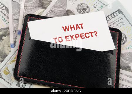 Concetto di business. COSA ASPETTARSI il testo su un biglietto da visita in un accessorio in pelle nera sullo sfondo dei dollari americani Foto Stock