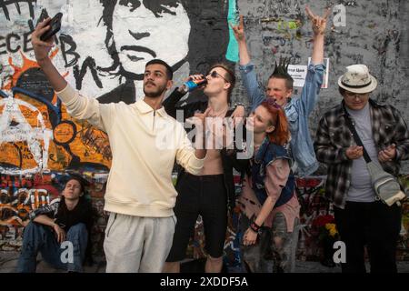 Mosca, Russia. 21 giugno 2024. Un turista straniero viene fotografato con giovani russi informali sullo sfondo del muro di Viktor Tsoi in Arbat Street, in occasione dell'anniversario del compleanno di Viktor Tsoi, nel centro di Mosca, Russia Foto Stock