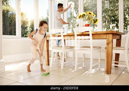 Pulizia, padre e insieme a figlia in cucina, spazzare e lavare la finestra, scopa e incollaggio. Casa, uomo e insegnamento dell'igiene ai bambini Foto Stock