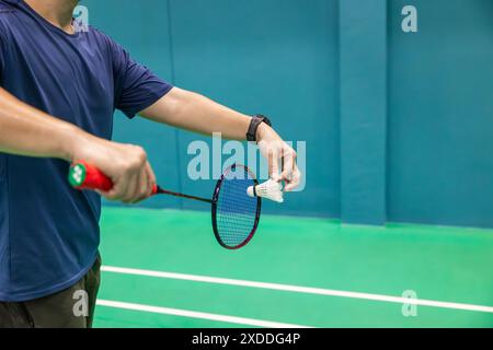 Giocatore di badminton mano che tiene in mano il rubinetto e la racchetta da badminton professionale sul campo da badminton sportivo al coperto Foto Stock