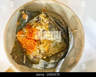 Riso fritto avvolto in foglie di loto su un piatto di ceramica. Foto Stock