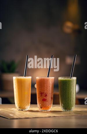 Tre frullati di frutta colorati con cannucce nere serviti sul tavolo del ristorante Foto Stock