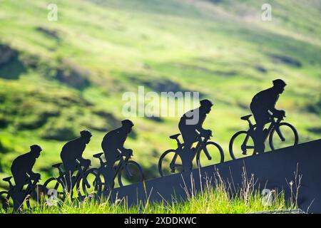 Lanslebourg-Mont-Cenis , Francia - 20 giugno 2024: Un gruppo di ciclisti affronta la ripida salita alpina sotto la luce posteriore. Foto Stock